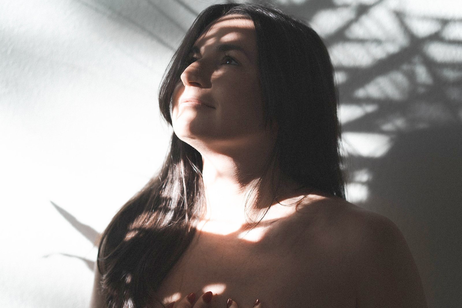Jade Levinson with her face tipped up into sunlight and leaf shadows, eyes closed