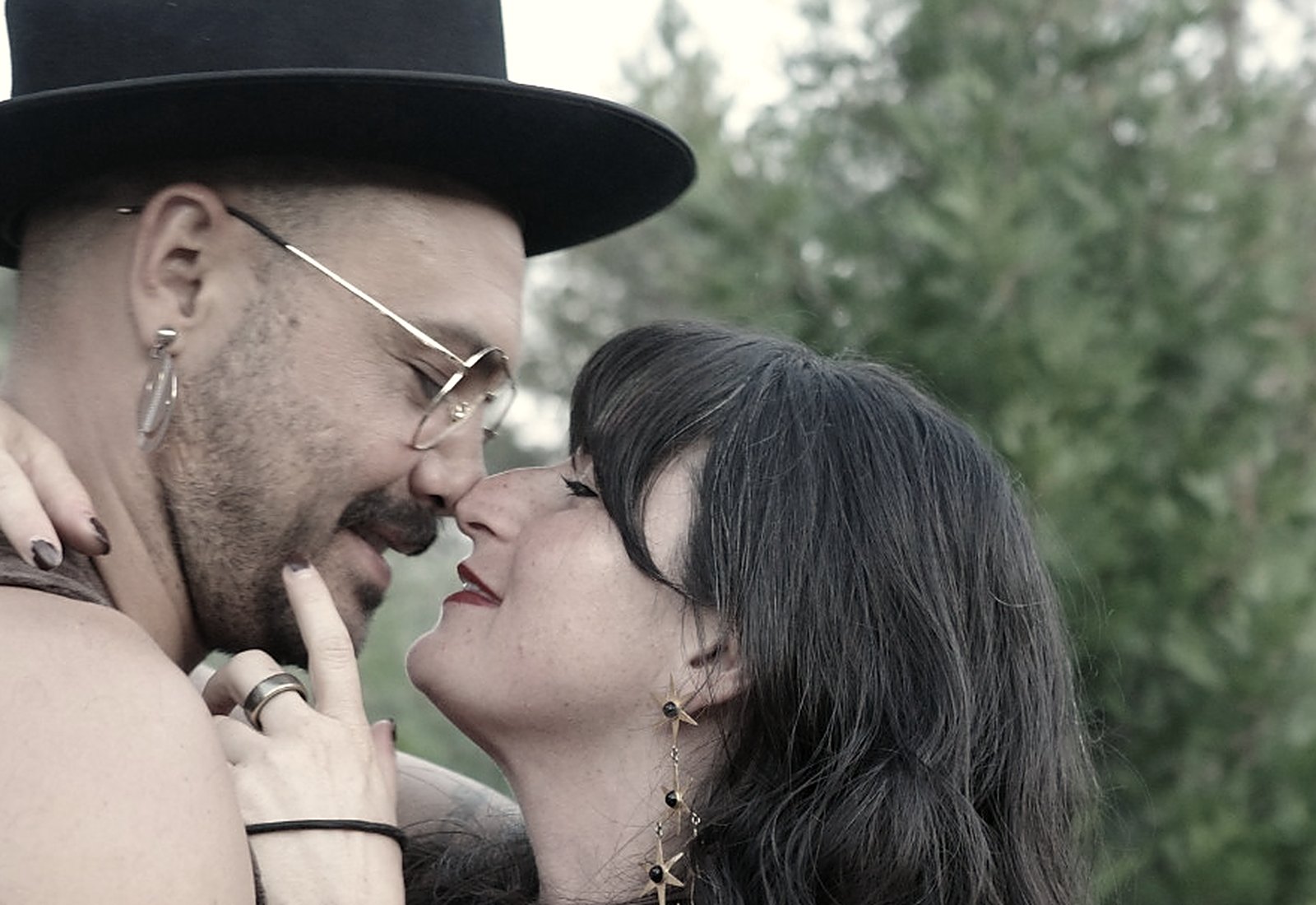 Jade Levinson and her partner Jamie nose to nose among pine and madrone trees, both smiling